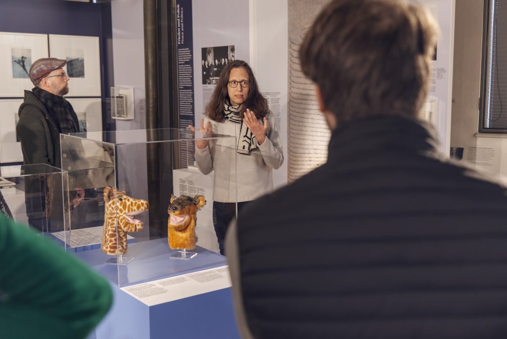 Eine Gruppe Menschen in einem Raum mit Vitrinen in weiß und blau