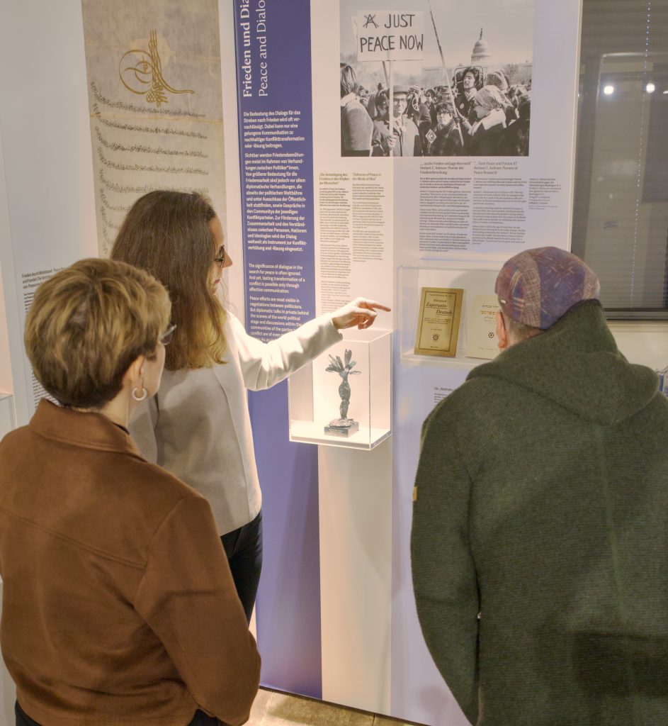Eine Gruppe Menschen in einem Raum mit Vitrinen in weiß und blau