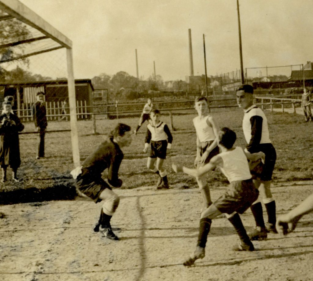 Sepia-Foto mit Fußballspielenden Männern vor einem Tor